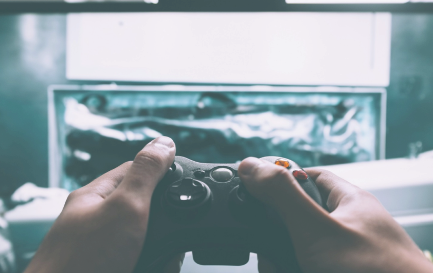 A hand with a Game pad and a Tv displaying the game